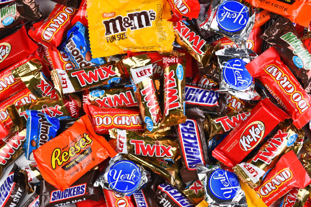 Assorted Halloween candy including Twix, Snickers, M&Ms, Reese's, Kit Kat, and Dum Dums